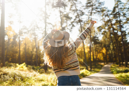 Happy woman enjoying autumn weather in the sunny park. Enjoying nature. Fashion, style concept. Happy woman enjoying autumn weather in the sunny park. Enjoying nature. Fashion, style concept. 131114564