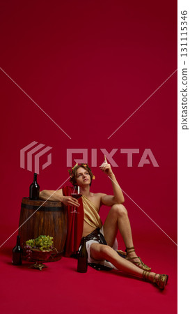 Young man in toga raising finger while holding wine glass in antique style 131115346