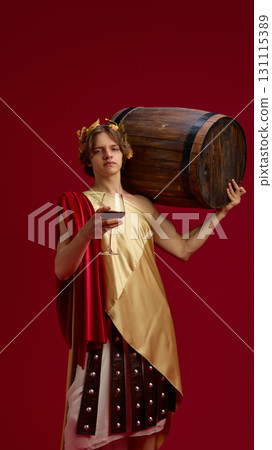 Young man in ancient toga carrying large wooden barrel and holding wine glass 131115389