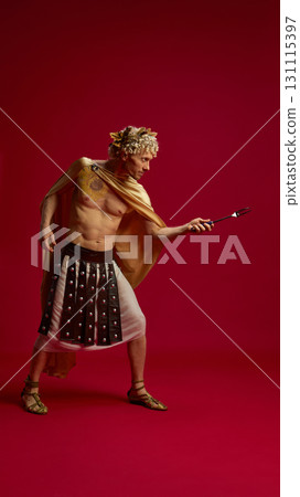 Man in Caesar costume posing with fork like gladiator weapon 131115397
