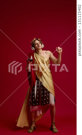 Man in ancient toga dancing with headphones and wine glass 131115402