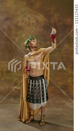 Man in Caesar toga holding grape-shaped decanter raised high with proud look 131115435