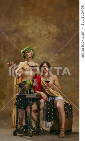Two men in Roman costumes with grapes and wine at festive banquet table 131115450