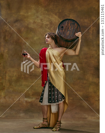 Man in Roman toga holding wine glass and carrying large wooden barrel on shoulder. 131115461