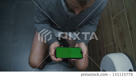 Businessman Sitting on the Toilet, Using Smartphone with Green Screen 131115778