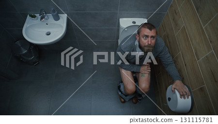 Man Taking Off Pants, Sitting on Toilet, Experiencing Diarrhea and Digestive Discomfort Man Taking Off Pants, Sitting on Toilet, Experiencing Diarrhea and Digestive Discomfort 131115781