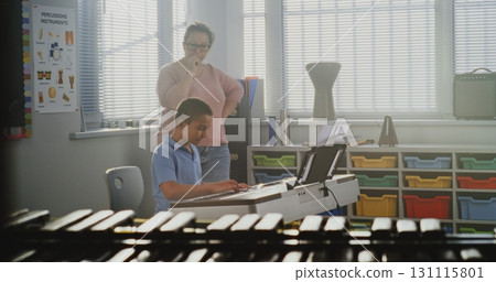 Music Teacher Guiding Primary School Boy to Play Piano in Music Class 131115801