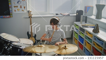 Primary School Boy Wearing Headphones Practicing Drums in Modern Music Class Primary School Boy Wearing Headphones Practicing Drums in Modern Music Class 131115957