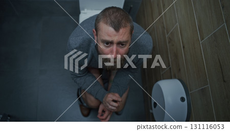 Businessman with Tense Facial Expression Suffering from Diarrhea and Indigestion, Sitting on the Toilet Businessman with Tense Facial Expression Suffering from Diarrhea and Indigestion, Sitting on the Toilet 131116053