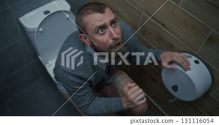 Businessman with Tense Facial Expression Suffering from Diarrhea and Indigestion, Sitting on the Toilet Businessman with Tense Facial Expression Suffering from Diarrhea and Indigestion, Sitting on the Toilet 131116054