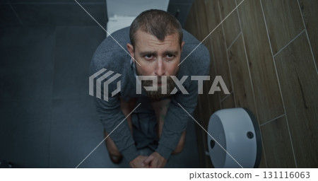 Businessman with Tense Facial Expression Suffering from Diarrhea and Indigestion, Sitting on the Toilet Businessman with Tense Facial Expression Suffering from Diarrhea and Indigestion, Sitting on the Toilet 131116063