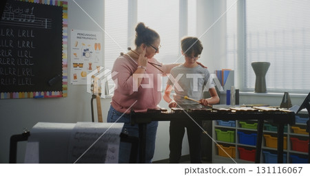 Primary School Boy Practicing Xylophone in Modern Music Class. Female Teacher Guiding Talented Student Primary School Boy Practicing Xylophone in Modern Music Class. Female Teacher Guiding Talented Student 131116067