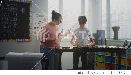 Primary School Boy Practicing Xylophone in Modern Music Class. Female Teacher Guiding Talented Student Primary School Boy Practicing Xylophone in Modern Music Class. Female Teacher Guiding Talented Student 131116071