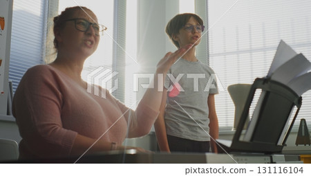 Primary School Boy Practicing Vocals During Singing Lesson. Music Teacher Playing Piano Primary School Boy Practicing Vocals During Singing Lesson. Music Teacher Playing Piano 131116104