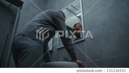 Businessman Looking in the Mirror, Washing His Hands with Soap in Restroom of Modern Office 131116141
