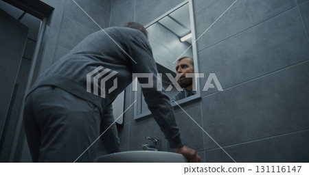 Businessman Looking in the Mirror, Washing His Hands with Soap in Restroom of Modern Office 131116147