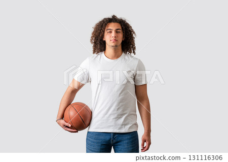 Confident young man holding basketball in casual outfit isolated on white background 131116306