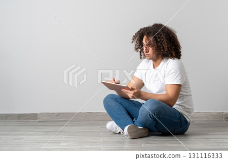Young man sitting on floor writing or drawing on digital tablet with stylus 131116333