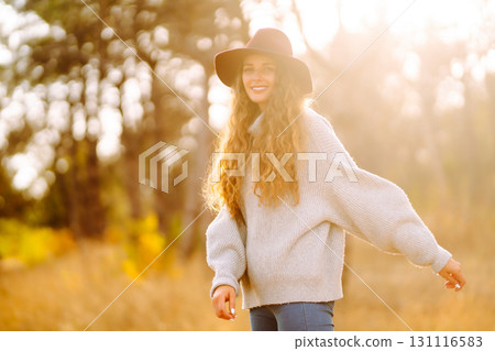 Stylish woman in sweater and hat enjoys autumn nature. People, freedom, lifestyle, travel concept. Stylish woman in sweater and hat enjoys autumn nature. People, freedom, lifestyle, travel concept. 131116583