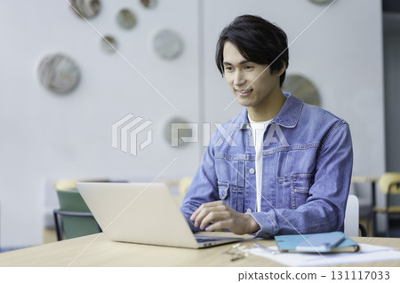 A young man using a laptop computer in an office cafe. Photo courtesy of Sky Perfect Tokyo Media Center 131117033