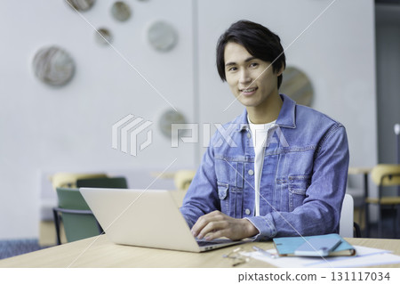 A young man using a laptop computer in an office cafe. Photo courtesy of Sky Perfect Tokyo Media Center 131117034
