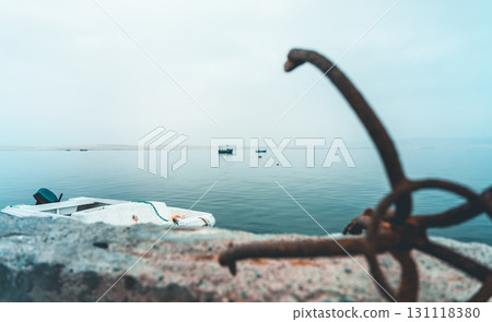 A rusty anchor is on the side of a wall next to a body of water A rusty anchor is on the side of a wall next to a body of water 131118380
