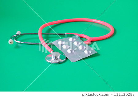 A blister pack of pills and pink stethoscope . 131120292