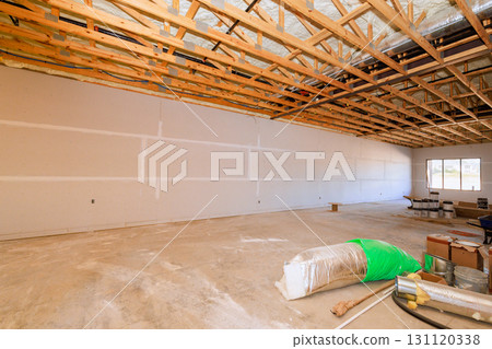 Large room under construction features exposed wooden beams bare walls as workers prepare for finishing touches. 131120338