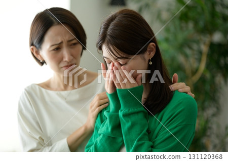 Crying woman and a Japanese woman comforting her 131120368