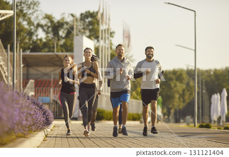 Group of young and sportive men and women jogging outdoors 131121404
