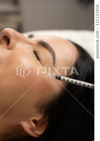Close-up of a woman receiving a cosmetic injection near the eye area. A syringe is applied to the skin for beauty treatment, anti-aging care, and wrinkle reduction, symbolizing modern aesthetics and Close-up of a woman receiving a cosmetic injection near the eye area. A syringe is applied to the skin for beauty treatment, anti-aging care, and wrinkle reduction, symbolizing modern aesthetics and 131121410