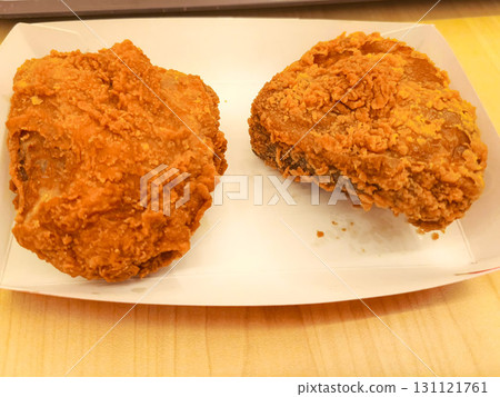 Golden crispy fried chicken served on a white tray over wooden surface. Close-up highlights crunchy texture and savory appeal of classic comfort food. 131121761