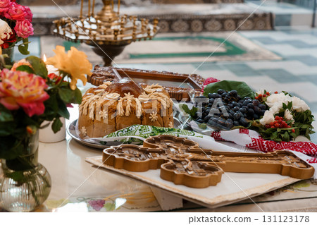 Ukrainian Traditional Easter Bread Kulich with Flowers, Grapes, and Pastry Cutters on Marble Table 131123178