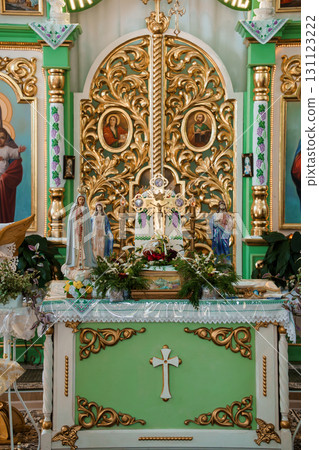 Elaborate Green and Gold Church Altar with Religious Icons, Statues, and Floral Arrangements. Catholic Worship Interior 131123222