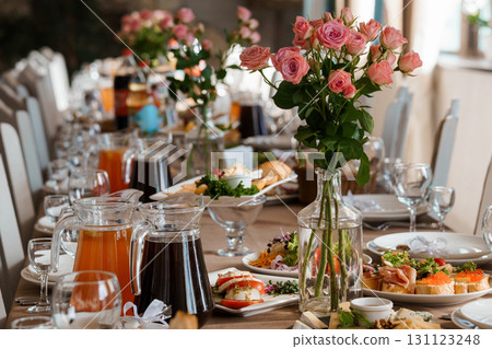 Elegant Wedding Reception Table Setting with Pink Roses, Fresh Food, and Orange Juice on a Luxurious Banquet Scene 131123248