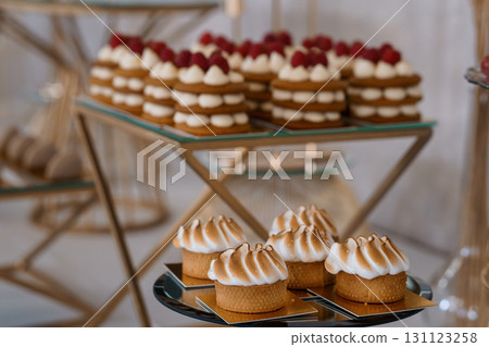 Elegant Raspberry Cream Cakes Displayed on Gold Stand, White Meringue Desserts, Fine Dining, Luxury Pastry, Wedding Table Setting. Elegant Raspberry Cream Cakes Displayed on Gold Stand, White Meringue Desserts, Fine Dining, Luxury Pastry, Wedding Table Setting. 131123258
