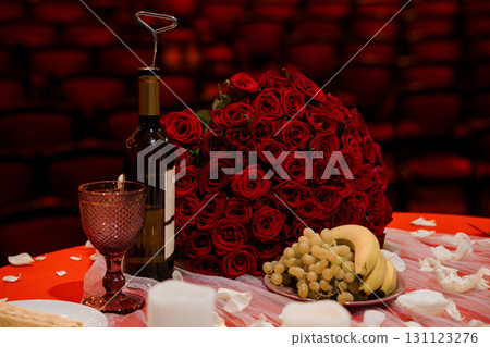 Romantic Valentine's Day Setup: Red Roses, Wine, Grapes, and Glass on Table with Brick Wall Background 131123276