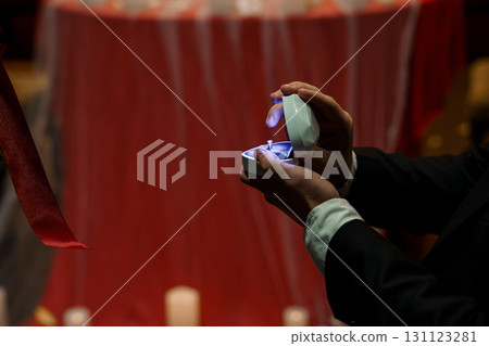 Romantic Marriage Proposal Scene with Illuminated Ring Box Against Red Drapery and Candlelight. Love, Engagement, Commitment. Romantic Marriage Proposal Scene with Illuminated Ring Box Against Red Drapery and Candlelight. Love, Engagement, Commitment. 131123281
