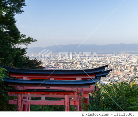 View from sacred Mount Inari forest in Kyoto with vermilion torii roofs and hazy urban landscape 131123303