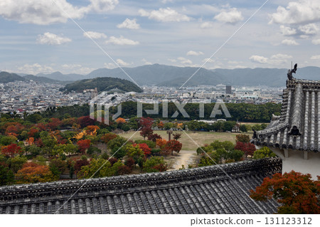 Himeji Castle park panorama showing autumn trees city skyline and distant mountains under blue sky 131123312
