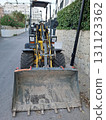 A mini excavator is parked on a narrow street in a residential neighborhood. The machine is ready for digging and construction tasks in the area. 131123362
