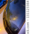Water droplets cover a car window while reflecting a streetlight at night, creating a shimmering effect in a quiet city scene. The atmosphere is calm and moody. 131123364
