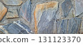 This wall features a striking arrangement of natural stone pieces with a variety of colors and textures. It serves as an attractive backdrop, adding character to any space. 131123370
