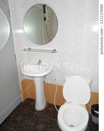A Compact Bathroom Featuring a White Sink and Toilet with a Round Mirror Above 131123666