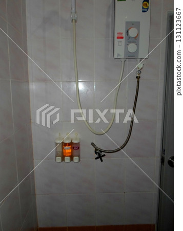 A Shower Setup with a Water Heater and Wall Mounted Soap Dispensers in a Tiled Bathroom 131123667