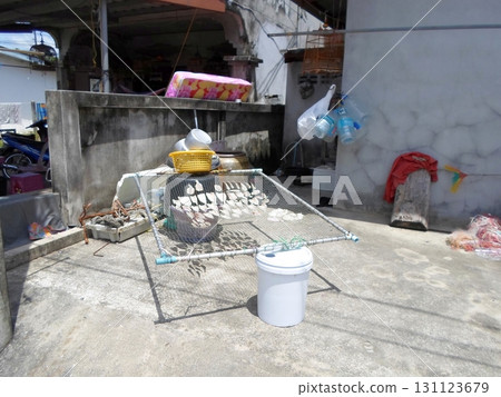 Fish Drying on a Net Frame in a Cluttered Outdoor Yard with Household Items Nearby Fish Drying on a Net Frame in a Cluttered Outdoor Yard with Household Items Nearby 131123679