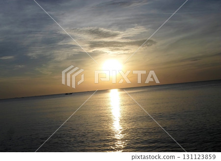 A Peaceful Ocean Sunset with a Distant Boat and a Reflective Path of Light on the Water A Peaceful Ocean Sunset with a Distant Boat and a Reflective Path of Light on the Water 131123859