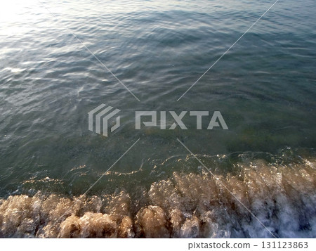 A Closeup of Gentle Ocean Waves Lapping at the Shore with a Soft Evening Glow A Closeup of Gentle Ocean Waves Lapping at the Shore with a Soft Evening Glow 131123863