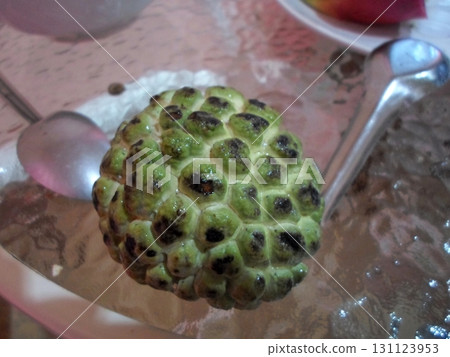 Whole Custard Apple on a Table with Spoons and a Lace Tablecloth in the Background Whole Custard Apple on a Table with Spoons and a Lace Tablecloth in the Background 131123953