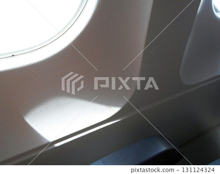 Sunlight Streaming Through an Airplane Window Casting Shadows on the Interior Wall 131124324